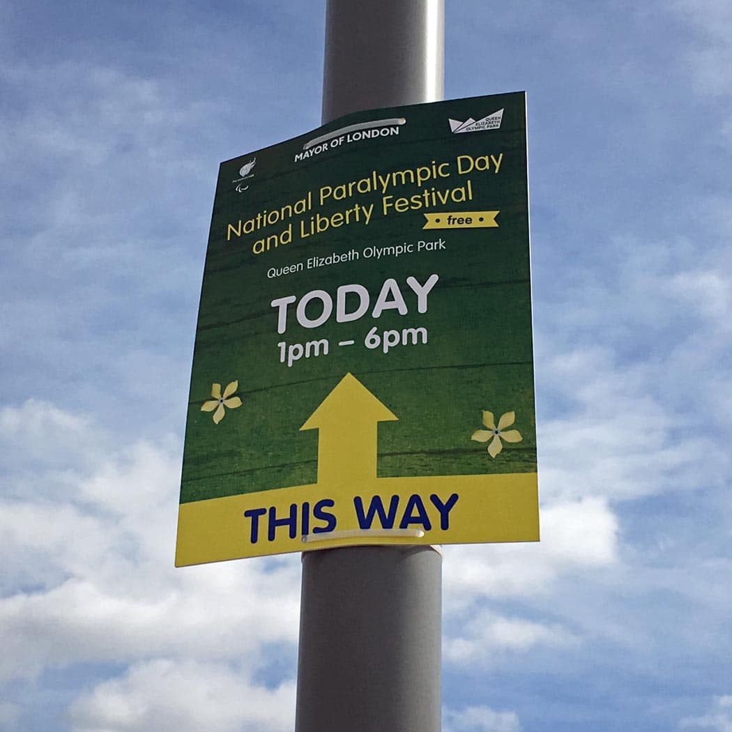 Green and yellow poster on a lampost, with an arrow saying National Paralympic Day and Liberty Festival.