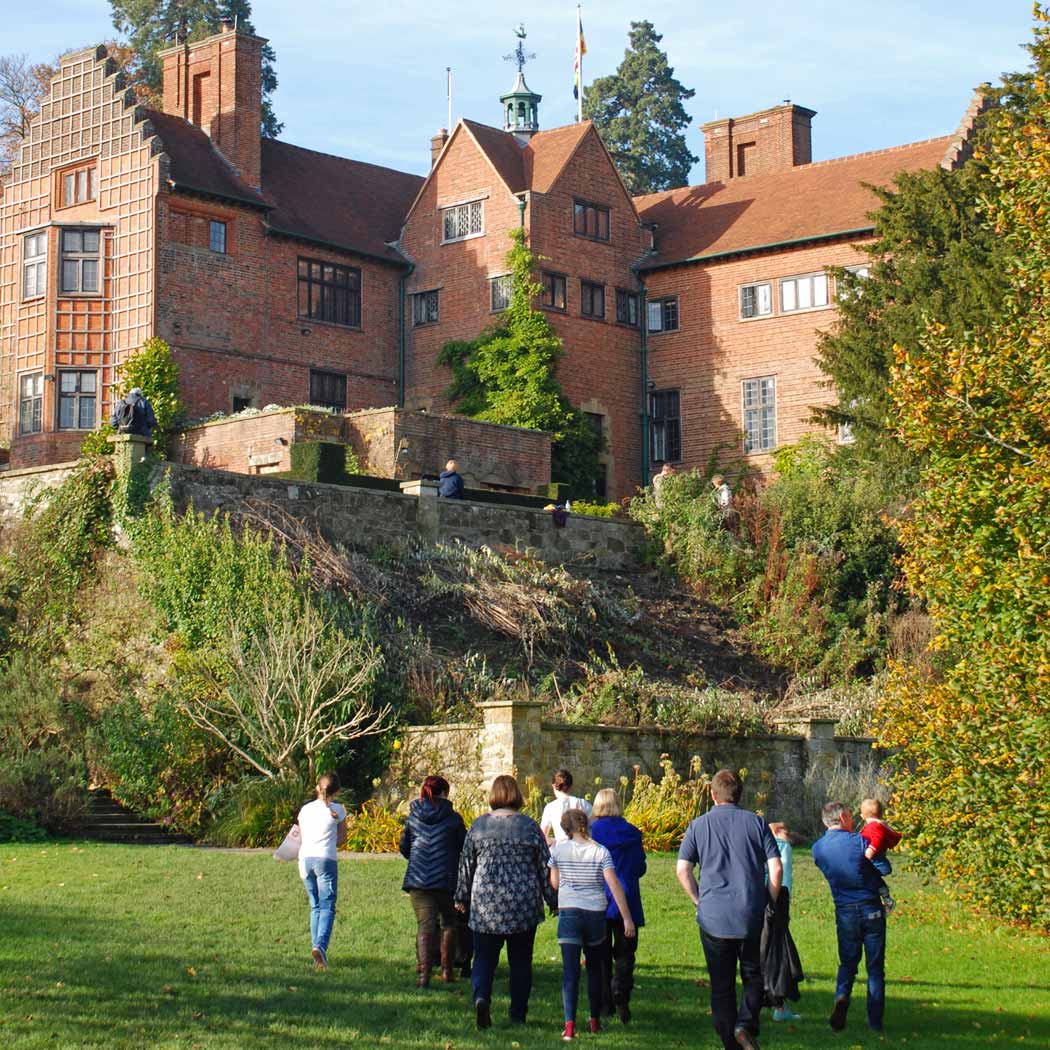 large red bricked house in foreground with extended family walking up to it.