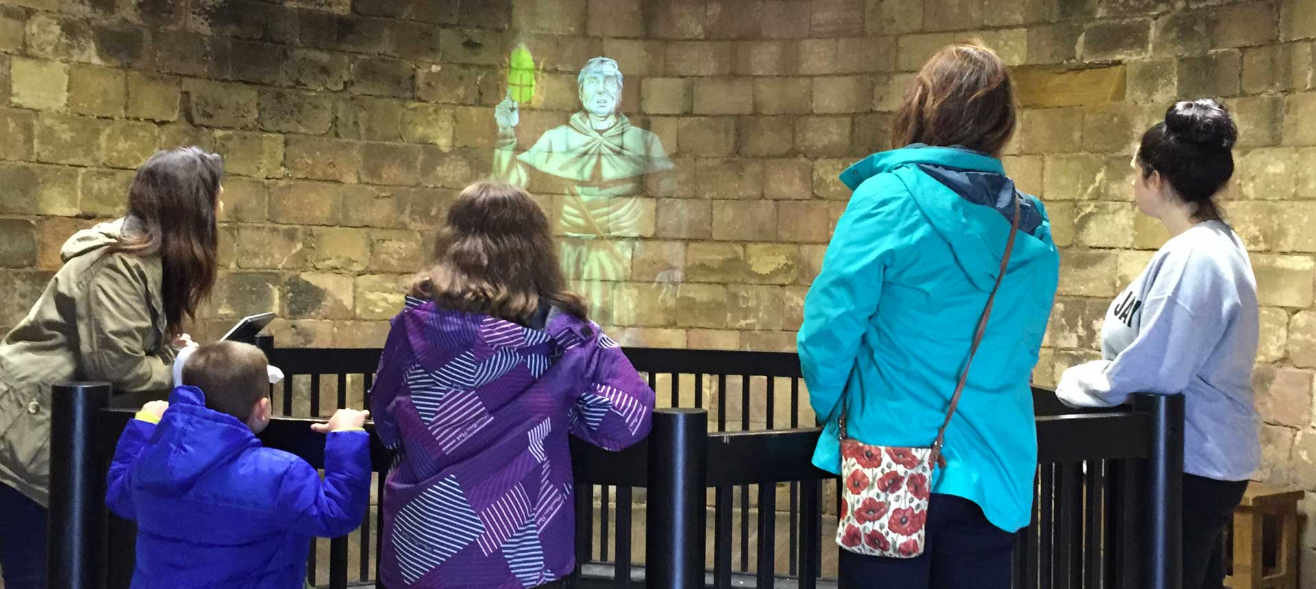 people looking at hologram on stone castle wall