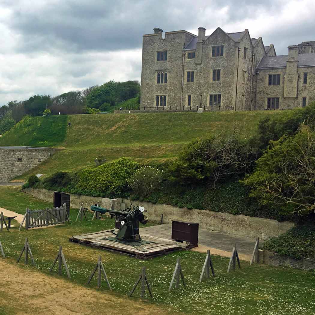 large castle set on a hill with cannon gun in front.