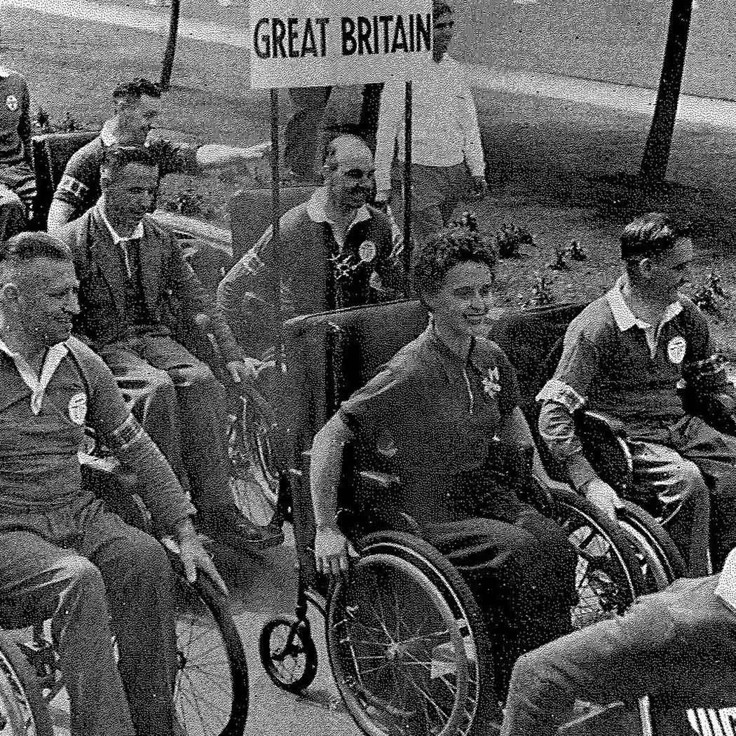 Men and women in wheelchairs, in uniform, beneath a Great Britain banner.