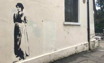 Stencilled image of Mary Wollstonecraft on a plain white wall.