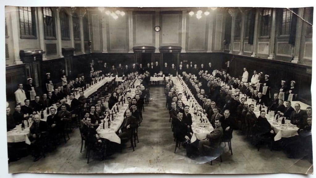 people dreesed in 40's clothing sitting at long laid dinner tables.