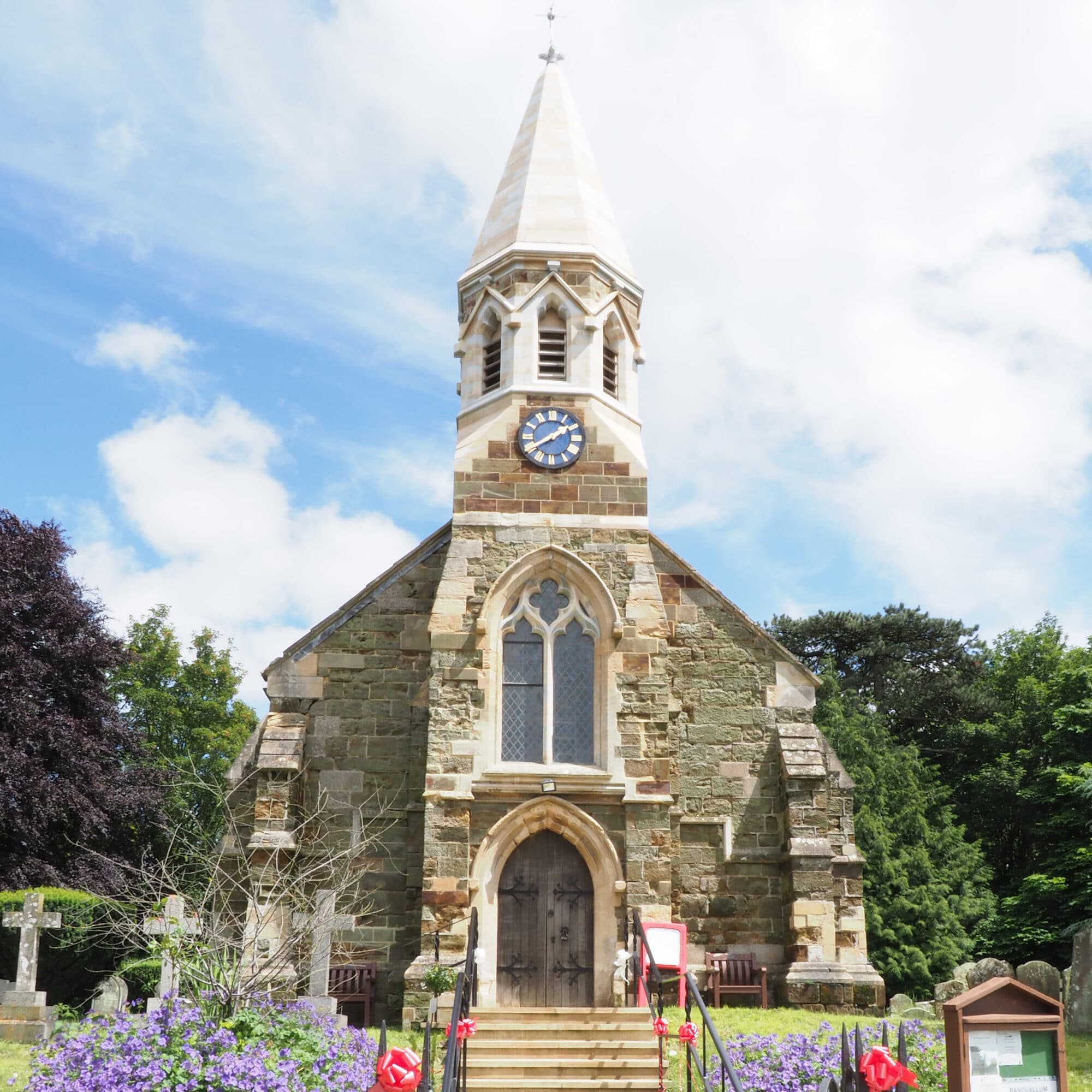 View looking up a flight of steps towards a church door with window and spire above. 