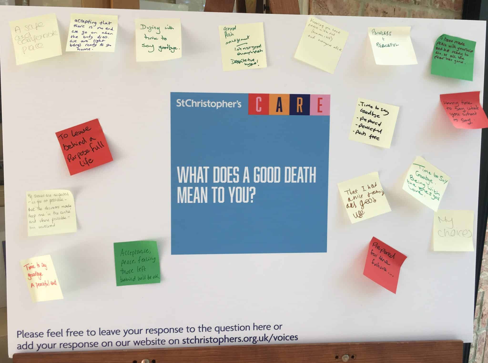 A white board with a question printed in the middle: What does a good death mean to you? Post it notes with handwritten answers are stuck on the board around the question. 